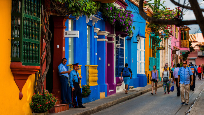 Tourists walk along the colorfully painted colonial houses in the street located within the historical walled city on December 12, 2017 in Cartagena, Colombia. After the peace agreement, ending a 52-year civil conflict and political stability in Colombia, Cartagena de Indias, a UNESCO World Heritage, experiences a tourism boom. The historic landmarks from the Spanish colonial times are being restored, private investments are visible in the city and an increased number of local people benefit from the boom of the travel related services. (Photo by Jan Sochor/Getty Images)