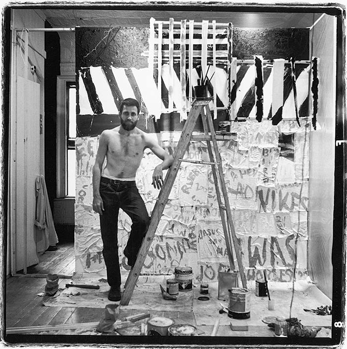 Portrait of American performance artist Allan Kaprow (1927 - 2006) as he stands with on foot on a ladder as he sets up an exhibition at the Ruben Gallery, New York, New York, September 10, 1959. The exhibition, entitled '18 Happenings in 6 Parts,' was an interactive art exhibition that ran for six performances between October 4 & 10, 1959. (Photo by Fred W. McDarrah/Getty Images)