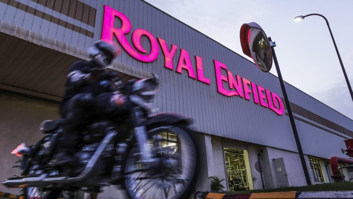 Production Line At Royal Enfield Motors Ltd. Factory As India Robot Invasion Undercuts Modi's Quest To Put Poor To Work...A motorcyclist rides past a Royal Enfield Motors Ltd. manufacturing facility in Chennai, India, on Tuesday, July 14, 2015. In a sweltering factory in southern India, Royal Enfield motorcycles are being painted and lacquered by giant robotic arms that move at twice the maximum speed of a human limb, day in, day out, never making a mistake. Photographer: Dhiraj Singh/Bloomberg