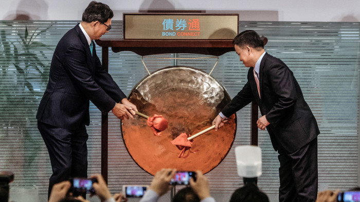 Norman Chan, chief executive of the Hong Kong Monetary Authority, left, and Pan Gongsheng, deputy governor of the People's Bank of China (PBOC), strike a gong during the launch ceremony of the China-Hong Kong Bond Connect at the Hong Kong Stock Exchange in Hong Kong, China on Monday, July 3, 2017. The first day of China’s new bond link to the rest of the world started on Monday, with little in the way of a market reaction. Photographer: Anthony Kwan/Bloomberg