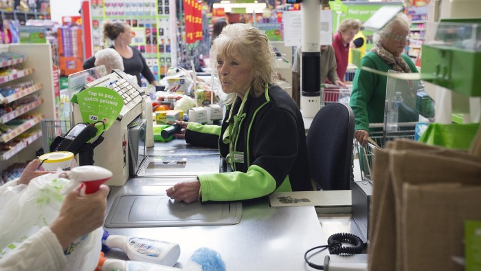 An employee scans a customer's purchases through a till at a check-out desk inside an Asda supermarket, the U.K. retail arm of Wal-Mart Stores Inc., in Watford, U.K., on Thursday, Oct. 17, 2013.