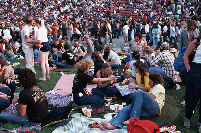 A group of spectators at California World Music Festival at the Los Angeles Memorial Stadium pass a pipe on the floor. (Photo by Henry Diltz/Corbis via Getty Images)