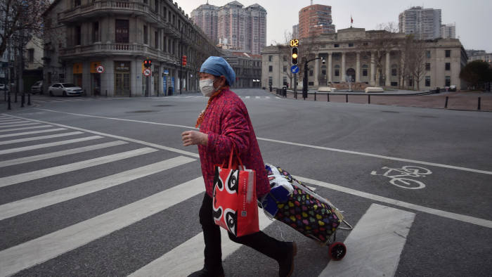 A person wearing a face mask walks across an empty intersection in Wuhan in central China's Hubei Province, Friday, Feb. 21, 2020. China's leadership sounded a cautious note Friday about the country's progress in halting the spread of the new virus that has now killed more than 2,200 people, after several days of upbeat messages. (Chinatopix via AP)