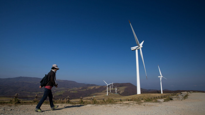 A woman walks toward wind turbines, manufactured by Vestas Wind Systems A/S and Unison Co., standing at Daegwanryeong Samyang Ranch in Pyeongchang, South Korea, on Friday, Nov. 1, 2013. South Korea wants a broader energy mix as it seeks to solve recurring supply shortages in Asia’s fourth-largest economy, the country’s energy minister said in October. Photographer: SeongJoon Cho/Bloomberg