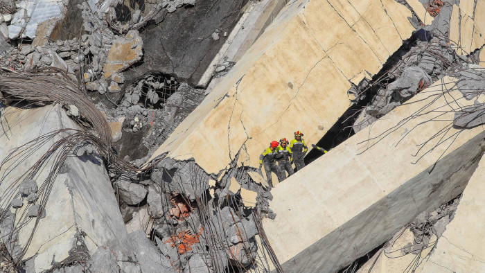 TOPSHOT - Italian rescuers climb onto the rubble of the collapsed Morandi motorway bridge to look for victims and survivors in the northern port city of Genoa on August 14, 2018. - At least 30 people were killed on August 14 when the giant motorway bridge collapsed in Genoa in northwestern Italy. The collapse of the viaduct, which saw a vast stretch of the A10 freeway tumble on to railway lines in the northern port city, was the deadliest bridge failure in Italy for years, and the country's deputy transport minister warned the death toll could climb further. (Photo by Valery HACHE / AFP) (Photo credit should read VALERY HACHE/AFP/Getty Images)