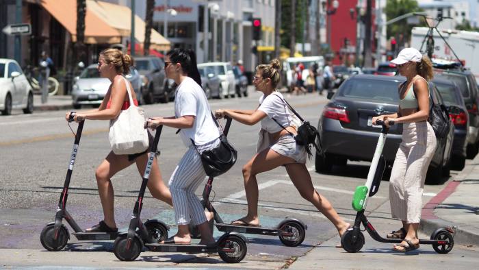 Young women ride shared electric scooters in Santa Monica, California, on July 13, 2018. - Cities across the U.S. are grappling with the growing trend of electric scooters which users can unlock with a smartphone app. Scooter startups including Bird and Lime allow riders to park them anywhere that doesn't block pedestrian walkways but residents in some cities, including Los Angeles, say they often litter sidewalks and can pose a danger to pedestrians. (Photo by Robyn Beck / AFP) (Photo credit should read ROBYN BECK/AFP/Getty Images)