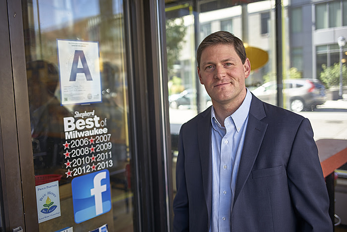 Andrew Lochowicz an EMBA student who helped create the algorithm that powers Milwaukee's new restaurant grading system poses next to the grading system in front of restaurants Wednesday, Oct. 9, 2019, in Milwaukee. (Darren Hauck for The Financial Times)