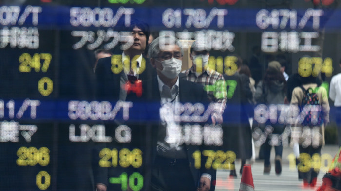 Pedestrians are reflected on an electronic stock quotation board at the window of a securities company in Tokyo on April 8, 2016. Tokyo stocks fell morning trade on April 8 as market heavyweight Fast Retailing, operator of the Uniqlo clothing chain, plunged more than 11 percent after forecasting a big decline in annual profit. / AFP / TOSHIFUMI KITAMURA 