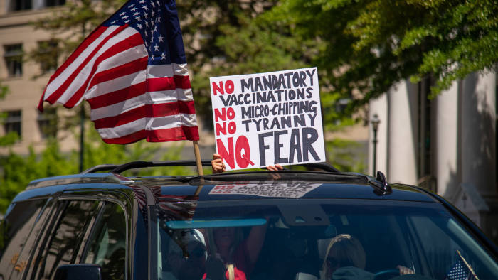 A woman holds a sign voicing various conspiracy theories believed by QAnon followers out of the sunroof of a car at the "Reopen Virginia" protest in Richmond on April 22nd, 2020. Three Percenters are a movement that advocates for constitutional rights, and takes its name from the belief that only three percent of America took up arms against the British during the Revolutionary War. (Photo by Matthew Rodier/Sipa USA)