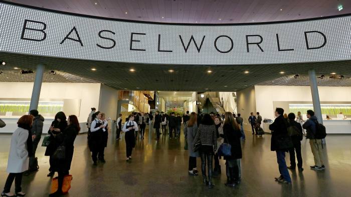 Visitors arrive at the main entrance of the Baselworld luxury watch and jewelry fair in Basel, Switzerland, on Wednesday, March 26, 2014. Over 1,400 companies from the watch, jewelry and gem industries will display their latest innovations and products to more than 120,000 visitors at this year's luxury show. Photographer: Gianluca Colla/Bloomberg