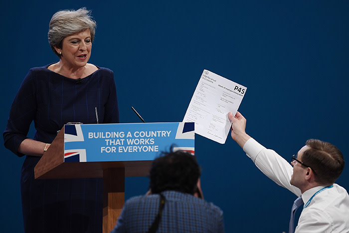MANCHESTER, ENGLAND - OCTOBER 04: Comedian Simon Brodkin, aka prankster Lee Nelson, hands Prime Minister Theresa May a P45 during her keynote speech to delegates and party members on the last day of the Conservative Party Conference at Manchester Central on October 4, 2017 in Manchester, England. The prime minister rallied members and called for the party to &quot;shape up&quot; and &quot;go forward together&quot;. Theresa May also announced a major programme to build council houses and a cap on energy prices. (Photo by Carl Court/Getty Images)***BESTPIX***