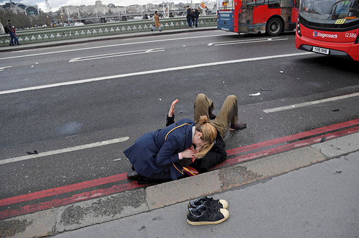 A woman assists an injured person after an incident on Westminster Bridge in London, Britain, March 22, 2017. Toby Melville: &quot;I was on the footpath below the southeast end of the bridge, shooting pictures for the on-going Brexit story. I saw in my peripheral vision a large dark shape around 3-5 metres away come over the parapet and hit the ground approximately 10 metres below. I thought it was a terrible but isolated accident. I immediately called for an ambulance and ran to the top of the steps to try to get help at St Thomas's, the nearby hospital. While on the phone, I saw a couple more people lying on the pavement amongst debris, covered in blood or unconscious. There were other people scattered along the bridge and pavement in various states of injury and distress. I realised this was not an accident but something premeditated. As the emergency services were on the scene now, I started taking photos along the bridge. I was unsure if danger was still present. I didn't know a car had been driven into these people. I hadn't heard any screams, loud engine noises or the gunshots of the armed police shooting and killing the perpetrator of the attack, Khalid Masood. I thought the injured or dead might also have been shot and a gunman might still be on the loose. Armed police arrived and cleared the bridge. I called the office and started filing photographs from the back of the camera, transmitting most of the frames I had shot for the office to choose, edit and crop. A week later I walked back over the bridge, everything was 'back to normal', in a way. But the sight of the first victim falling and the sickening thud as he hit the pavement still goes through my mind. I wonder whether I should have transmitted all the frames I shot. The sequence of pictures is hard to look at. I remind myself I was lucky. I had walked over the bridge about a minute before the attack. Others weren't so fortunate.&quot; REUTERS/Toby Melville/File photo SEARCH &quot;POY STORY&quot; FOR THIS STORY.