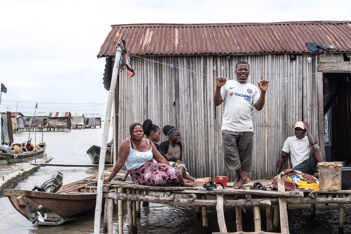 In the informal fishing community of Isale Ijebu in Ajah. Juliet sits outside her home with her family in front of their home of which they've been given an eviction notice.
