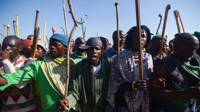 -...Striking miners hold sticks as they dance and sing during a protest against their labour conditions, in the Wonderkop stadium in Marikana, South Africa, on May 14, 2014. Thousands of club-wielding striking workers at a platinum mine in South Africa were urged by their leaders to remain steadfast in the face of a deadline to return underground today. AFP PHOTO / SKYLER REID