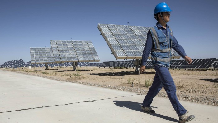 An employee walks past photovoltaic panels at a solar power station operated by Huanghe Hydropower Development Co., a unit of State Power Investment Corp., at the Golmud Solar Park on the outskirts of Golmud, Qinghai province, China, on Tuesday, July 24, 2018. China has emerged as the global leader in clean power investment after it spent $127 billion in renewable energy last year as it seeks to ease its reliance on coal and reduce smog in cities, according to a report jointly published by the United Nations and Bloomberg New Energy Finance in April. Photographer: Qilai Shen/Bloomberg
