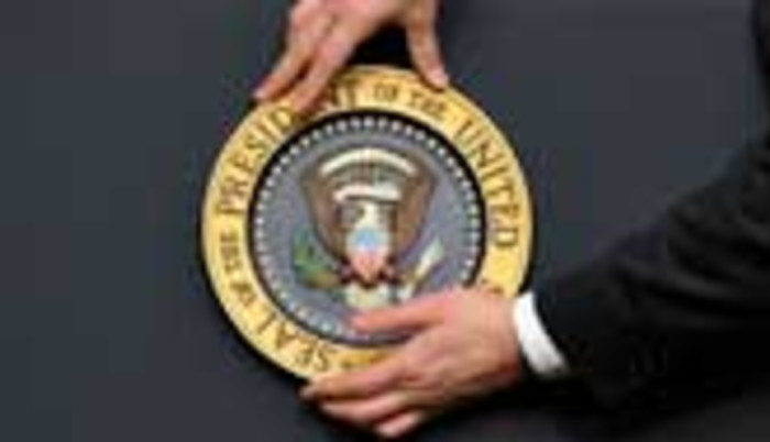staff fixes the presidential seal before US President Barack Obama gives a press conference 
