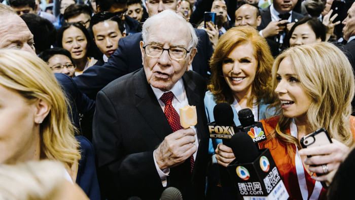 Warren Buffett, chairman and chief executive officer of Berkshire Hathaway Inc., center left, eats a Dairy Queen vanilla orange ice cream bar while touring the shopping floor ahead of the company's annual meeting in Omaha, Nebraska, U.S., on Saturday, May 4, 2019. Buffett's Berkshire Hathaway agreed earlier this week to make the investment in Occidental to help the oil producer with its $38 billion bid for Anadarko Petroleum Corp. Photographer: Houston Cofield/Bloomberg