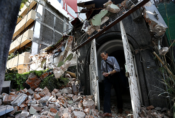 A man walks out of the door frame of a building that collapsed after an earthquake, in the Condesa neighborhood of Mexico City, Tuesday, Sept. 19, 2017. Throughout Mexico City, rescuer workers and residents dug through the rubble of collapsed buildings seeking survivors following a 7.1 magnitude quake. (AP Photo/Marco Ugarte)
