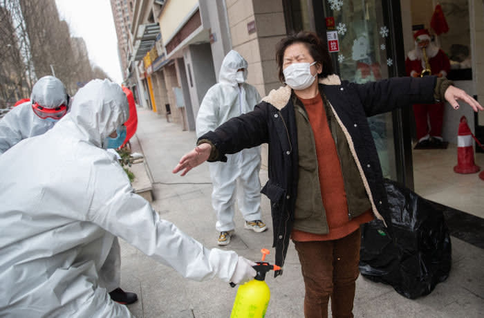 TOPSHOT - A woman (R), who has recovered from the COVID-19 coronavirus infection, is disinfected by volunteers as she arrives at a hotel for a 14-day quarantine after being discharged from a hospital in Wuhan, in China's central Hubei province on March 1, 2020. - China on March 1 reported 35 more deaths from the new coronavirus, taking the toll in the country to 2,870. (Photo by STR / AFP) / China OUT (Photo by STR/AFP via Getty Images)