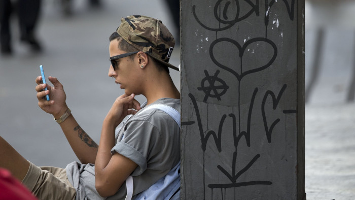 A youth checks his cell phone in Sao Paulo, Brazil, Thursday, Dec. 17, 2015.  Brazilians awoke to a day without WhatApp Thursday after a judge ordered the popular messaging app blocked throughout the country for 48 hours. In a statement, Sao Paulo's criminal court system said only that WhatsApp had been handed two prior judicial orders this year that the California-based company failed to heed. (AP Photo/Andre Penner)
