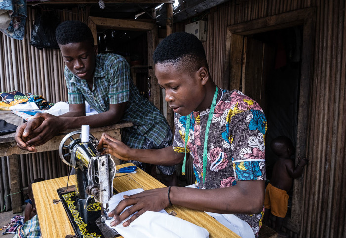 A tailor in the community makes use of the shared manual sewing machine used by Tinu, her extended family and their neighbours