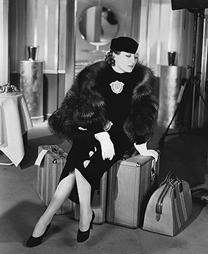 Joan Crawford (1904-1977) sitting on her luggage