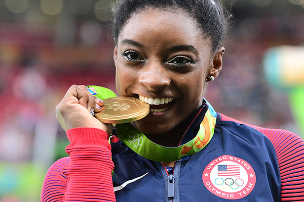 TOPSHOT - US gymnast Simone Biles celebrates with her gold medal after the women's individual all-around final of the Artistic Gymnastics at the Olympic Arena during the Rio 2016 Olympic Games in Rio de Janeiro on August 11, 2016.
US gymnast Simone Biles won the event ahead of her compatiot Alexandra Raisman and Russia's Aliya Mustafina. / AFP / Emmanuel DUNAND        (Photo credit should read EMMANUEL DUNAND/AFP/Getty Images)