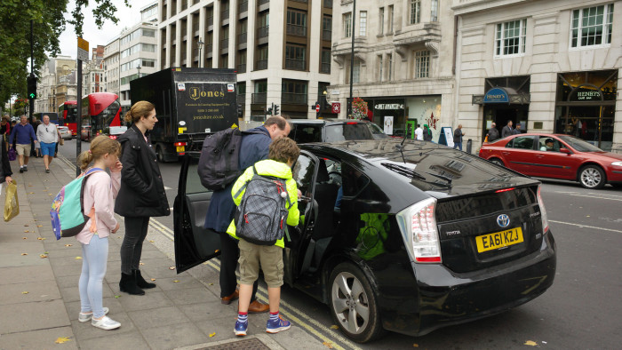 K6XNC6 Couple with children getting into a private cab in London, UK