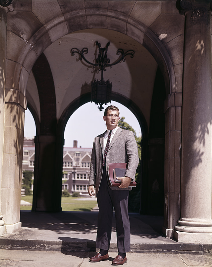 1960s MAN COLLEGE STUDENT STANDING NEAR ARCH LEADING TO COLLEGE CAMPUS QUADRANGLE (Photo by H. Armstrong Roberts/ClassicStock/Getty Images)
