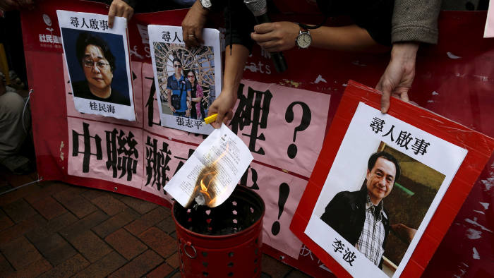 A pro-democracy demonstrator burns a letter next to pictures of missing staff members of a publishing house and a bookstore during a protest to call for an investigation behind their disappearance, outside the Chinese liaison office in Hong Kong...A pro-democracy demonstrator burns a letter next to pictures of missing staff members of a publishing house and a bookstore, including Gui Minhai, a China-born Swedish national who is the owner of Mighty Current, Cheung Jiping, the business manager of the publishing house and Causeway Bay Books shareholder Lee Bo (L-R), during a protest to call for an investigation behind their disappearance, outside the Chinese liaison office in Hong Kong, China January 3, 2016. Hong Kong opposition lawmakers protested on Sunday outside Beijing's representative office in the Chinese-ruled city over the disappearance of a bookseller who specializes in publications critical of the Communist Party government. REUTERS/Tyrone Siu