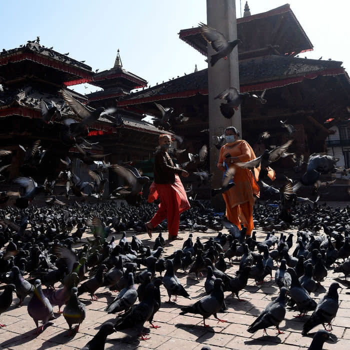 Women wearing facemasks feed pigeons in Durbar Square during a government-imposed nationwide lockdown as a preventive measure against the COVID-19 coronavirus, in Kathmandu on April 19, 2020 (Photo by PRAKASH MATHEMA / AFP) (Photo by PRAKASH MATHEMA/AFP via Getty Images)