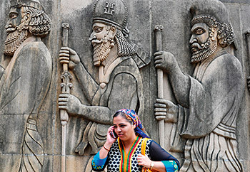 An Indian Parsi devotee talks on the phone as she stands in front of a sculpture after offering prayers at a fire temple on the Parsi New Year 'Navroze' in Mumbai on August 18, 2014