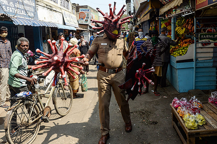 TOPSHOT - A policeman (C) wearing a coronavirus-themed outfit composed of helmet, mace and shield, walks at a market to raise awareness about social distancing, during a government-imposed nationwide lockdown as a preventive measure against the COVID-19 coronavirus, in Chennai on April 2, 2020. (Photo by Arun SANKAR / AFP) (Photo by ARUN SANKAR/AFP via Getty Images)