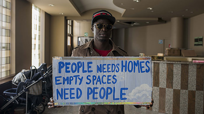 A refugee holds a placard reads &quot;People needs Homes, Empty Spaces need people&quot; inside the Hotel astrid that occupied by refugees in the city center of Brussels, Belgium, 25 September 2017. Photo: Jean-Marc Herve Abelard/BELGA/dpa
