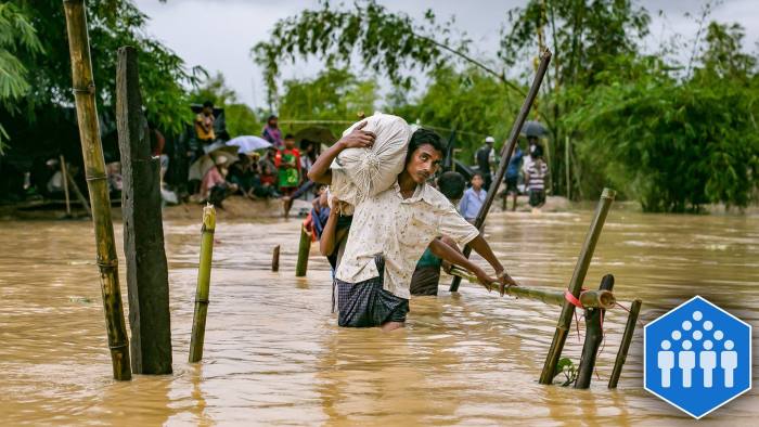 COX'S BAZAR, BANGLADESH - SEPTEMBER 19: Refugees cross a flooded bridge in the Balukhali Rohingya refugee camp on September 19, 2017 in Cox's Bazar, Bangladesh. Over 400,000 Rohingya refugees have fled into Bangladesh since late August during the outbreak of violence in the Rakhine state as Myanmar's de facto leader Aung San Suu Kyi broke her silence on the Rohingya crisis on Tuesday and defended the security forces while criticism on her handling of the Rohingya crisis grows. Recent satellite images released by Amnesty International provided evidence that security forces were trying to push the minority Muslim group out of the country. (Photo by Allison Joyce/Getty Images)