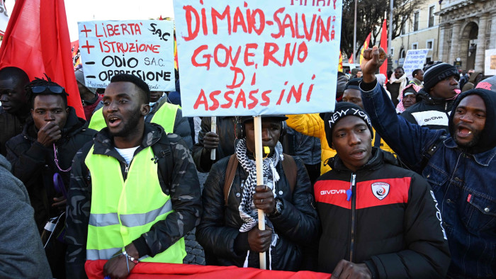People, members of anti-racism associations and migrants gather on Piazza della Repubblica in central Rome on December 15, 2018 to protest the government's social politics, its recent decree restricting the right to asylum, and against racism. - The placard reads &quot;Di Maio, Salvini, government of assassins&quot;. (Photo by Vincenzo PINTO / AFP)VINCENZO PINTO/AFP/Getty Images