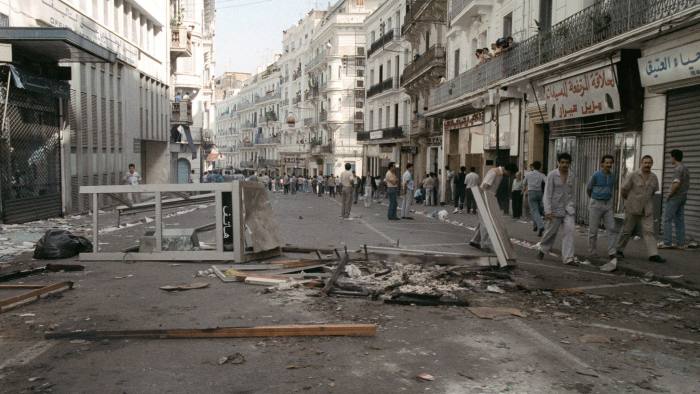 ALGIERS, ALGERIA: Riot policemen deploy in the streets of Algiers 10 October 1988, and one of them (behind) fires tear as. Security forces shot dead at least 25 people during its demonstration. AFP PHOTO (Photo credit should read AFP/Getty Images)