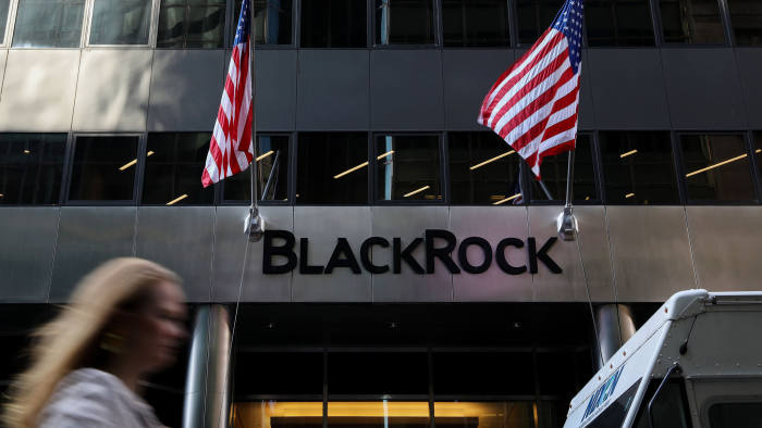 A pedestrian walks past American flags flying at BlackRock Inc. headquarters in New York, U.S, on Wednesday, June 11, 2018. BlackRock Inc. is scheduled to release earnings figures on July 16. Photographer: Bess Adler/Bloomberg