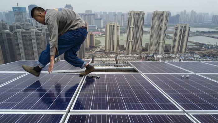 WUHAN, CHINA - MAY 15: A Chinese worker from Wuhan Guangsheng Photovoltaic Company works on a solar panel project on the roof of a 47 story building in a new development on May 15, 2017 in Wuhan, China. China consumes more electricity than any other nation, but it is also the world's biggest producer of solar energy. Capacity in China hit 77 gigawatts in 2016 which helped a 50% jump in solar power growth worldwide. China is now home to two-thirds of the world's solar production, though capacity and consumption remain low relative to its population. Still, the country now buys half of the world's new solar panels which convert sunlight into energy, and are being installed on rooftops in cities and across sprawling fields in rural areas. Greenpeace estimates that by 2030, renewable energy could replace fossil fuels as China's primary source of power, a significant change in a country considered the world's biggest polluter. China's government has officially committed to development of renewable energies to ease the country's dependence on coal and other fossil fuels, though its strategic investments in the solar panel have created intense global competition. (Photo by Kevin Frayer/Getty Images)