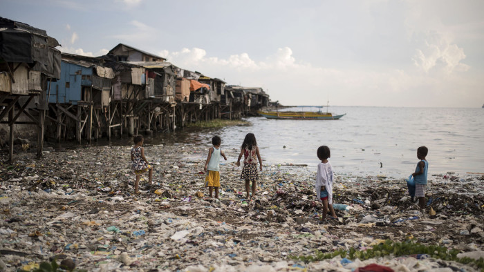 This photo taken on May 9, 2018 shows children walking on garbage filled bay in Manila. (Photo by NOEL CELIS / AFP) (Photo credit should read NOEL CELIS/AFP via Getty Images)