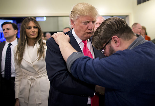 FILE - In this Jan. 31, 2016, file photo, Pastor Joshua Nink, right, prays for Republican presidential candidate Donald Trump, as his wife, Melania, left, watches after a Sunday service at First Christian Church, in Council Bluffs, Iowa. Trump's candidacy has put a harsh spotlight on the fractures among Christian conservatives, most prominently the rift between old guard religious right leaders who backed the GOP nominee as an ally on abortion, and a comparatively younger generation who considered his personal conduct and rhetoric morally abhorrent. (AP Photo/Jae C. Hong, File)