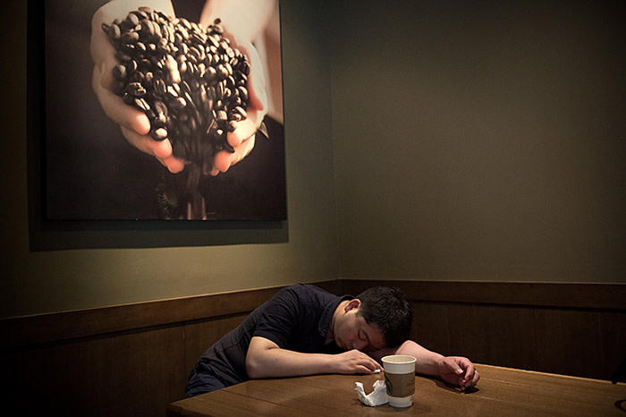 A man takes a nap after drinking a coffee inside a Starbucks in Beijing on June 28, 2017. / AFP PHOTO / NICOLAS ASFOURI (Photo credit should read NICOLAS ASFOURI/AFP/Getty Images)