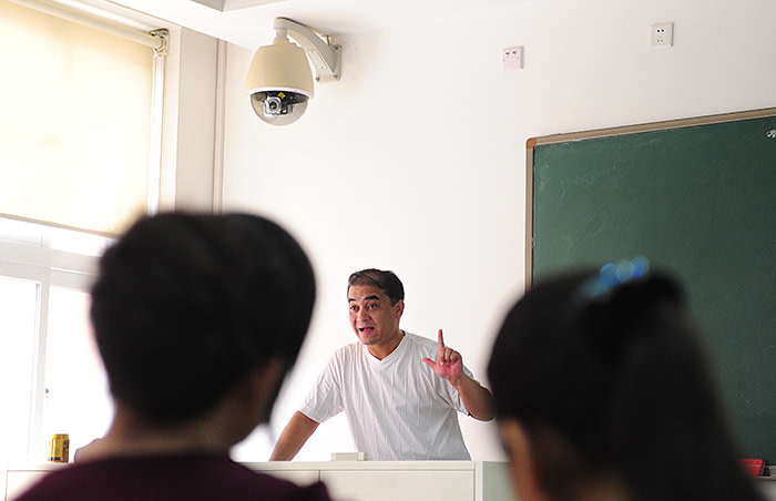 With a security surveillance camera mouted above the teacher's podium, university professor, blogger, and member of the Muslim Uighur minority, Ilham Tohti lectures in a classroom in Beijing on June 12, 2010. Perhaps the top Uighur activist within China, Tohti disappeared into police custody for six weeks last year after Uighur resentment burst forth last July in China's northwest Xinjiang province, in Central Asia, when Uighur rioters savagely attacked Han Chinese in the regional capital Urumqi, leaving nearly 200 people dead and up to 1,700 injured, according to official figures. AFP PHOTO/Frederic J. BROWN (Photo credit should read FREDERIC J. BROWN/AFP/Getty Images)