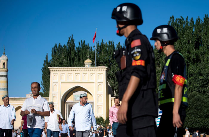 (FILES) This file photo taken on June 26, 2017 shows police (R) patrolling as Muslims leave the Id Kah Mosque after morning prayer during Eid al-Fitr in Kashgar in China's Xinjiang Uighur Autonomous Region. China's construction of a vast, all-seeing police state in its fractious far west has triggered a government spending spree worth billions to firms providing a hi-tech network of cameras and &quot;re-education centres&quot;. The surveillance machine in Xinjiang region has grown exponentially in recent years, used by the ruling Communist Party to guard against what it considers Islamic extremism and separatism in the region. / AFP PHOTO / JOHANNES EISELE / TO GO WITH: CHINA-SECURITY-RIGHTS; Focus by Ben DOOLEYJOHANNES EISELE/AFP/Getty Images