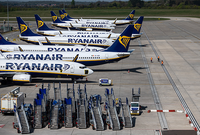 STANSTED, ESSEX - APRIL 15: Three people walk on the runway amongst parked and temporarily out of service Ryanair passenger aircraft at Stansted Airport on April 15, 2020 in Stansted, Essex. Passenger travel has plummeted amid the COVID-19 travel restrictions, but the are still a small number of flights at Stansted Airport each day, some repatriating Britons from abroad. (Photo by Chris J Ratcliffe/Getty Images)