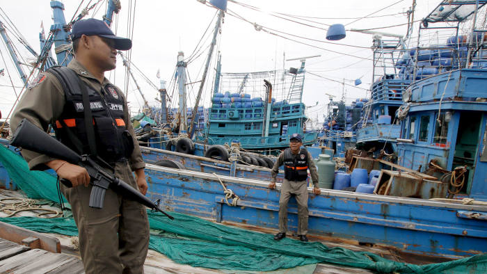 Police officers stand near a fishing boat during an inspection at the pier of Songkhla, south Thailand December 23, 2015