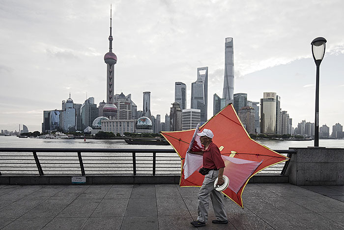 A man carries a kite along the bund as the Lujiazui Financial District stands in the background in Shanghai, China, on Monday, Sept. 4, 2017. 