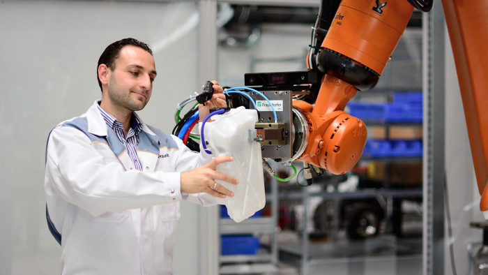 Good teamwork: The robot hands a component to its human colleague. Fraunhofer IWU