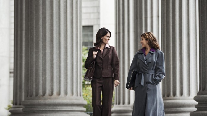 Two women walking in front of courthouse talking having a conversation
