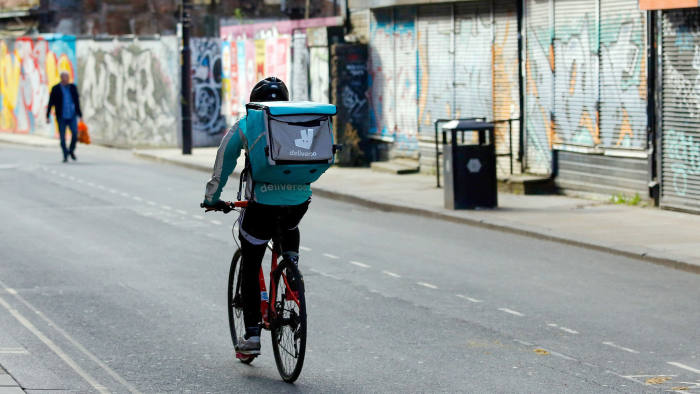 A food delivery courier for Deliveroo, operated by Roofoods Ltd., cycles in Manchester, U.K., on Wednesday, April 8, 2020. The U.K. has been racing to protect businesses and workers from the effects of the pandemic and the restrictions imposed to combat it. Photographer: Paul Thomas/Bloomberg